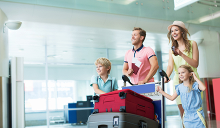 A happy family walking through an airport with luggage