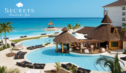 A tropical resort with a swim up bar, bright blue pool water and the ocean in the background