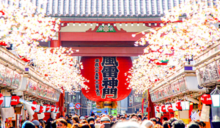 Cherry blossoms lining the streets in an Asian town setting with a crowd of people gathered