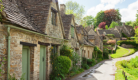 London town with stone homes lining a narrow road with lush landscaping