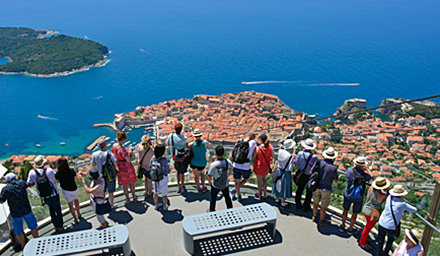 A group of people on an overlook looking out at beautiful blue waters in Europe