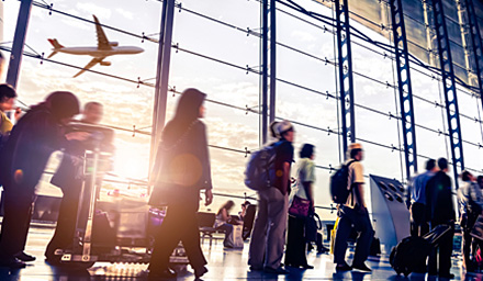 Travelers in a busy airport, large windows and a plane flying in the background