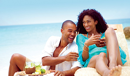 A cute couple enjoying some cocktails on the beach at Sandals Resort in the Caribbean